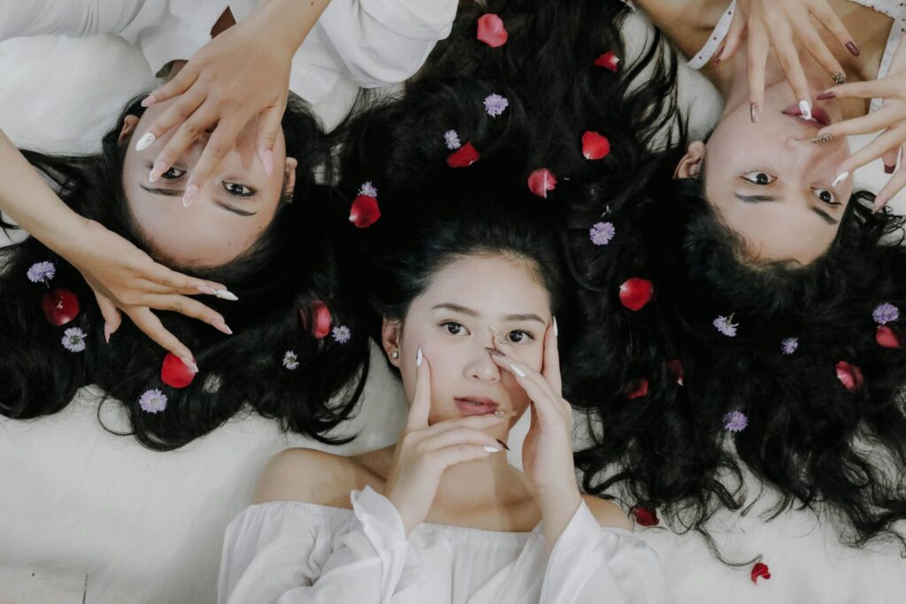 Artistic overhead portrait of three women with flower petals in Bali, Indonesia, conveying beauty and harmony.