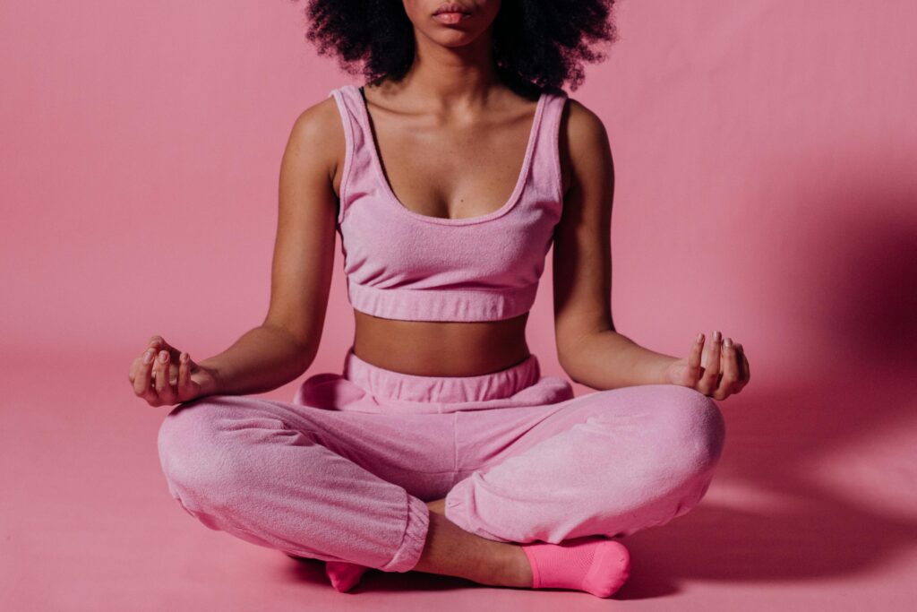 Young woman meditating in studio, embracing calmness and wellness in a pink outfit.