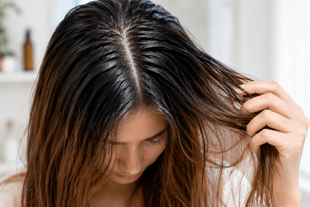 Woman examining combination hair with oily, shiny roots and visibly dry, brittle lengths and ends. Woman examining combination hair with oily, shiny roots and visibly dry, brittle lengths and ends.