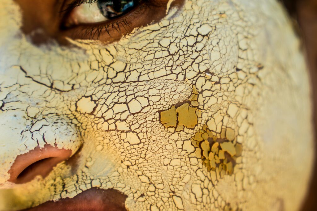 A detailed macro shot showing the intricate cracked texture of a dried face mask applied to human skin for skincare.