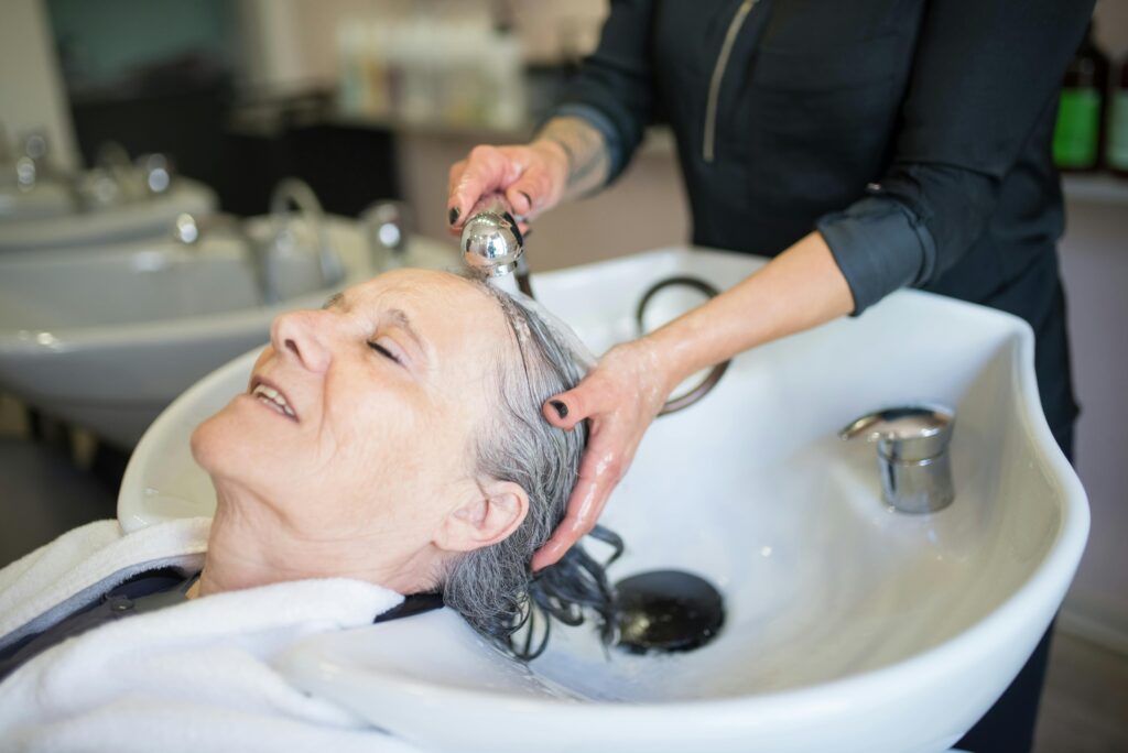 pexels-photo-8834048-8834048 Elderly woman enjoying a soothing hair wash in a stylish Portuguese salon, capturing a tranquil moment.