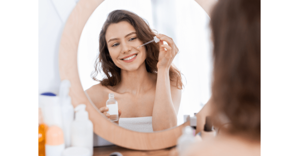 Woman applying facial serum as part of a daily skin care routine before moisturizer and sunscreen.