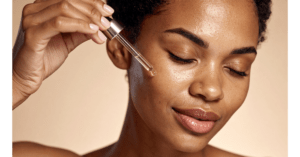 Woman applying facial serum as part of a daily skin care routine before moisturizer and sunscreen.